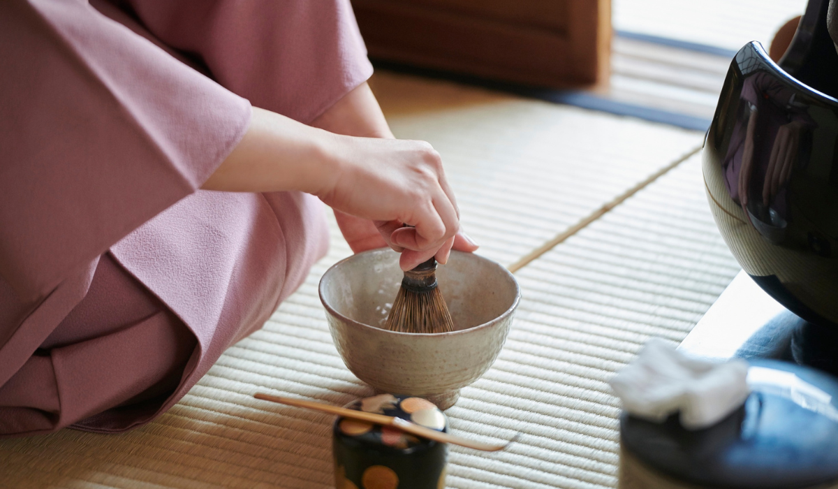 畳の上で茶筅を使って抹茶を点てる手元と茶道具